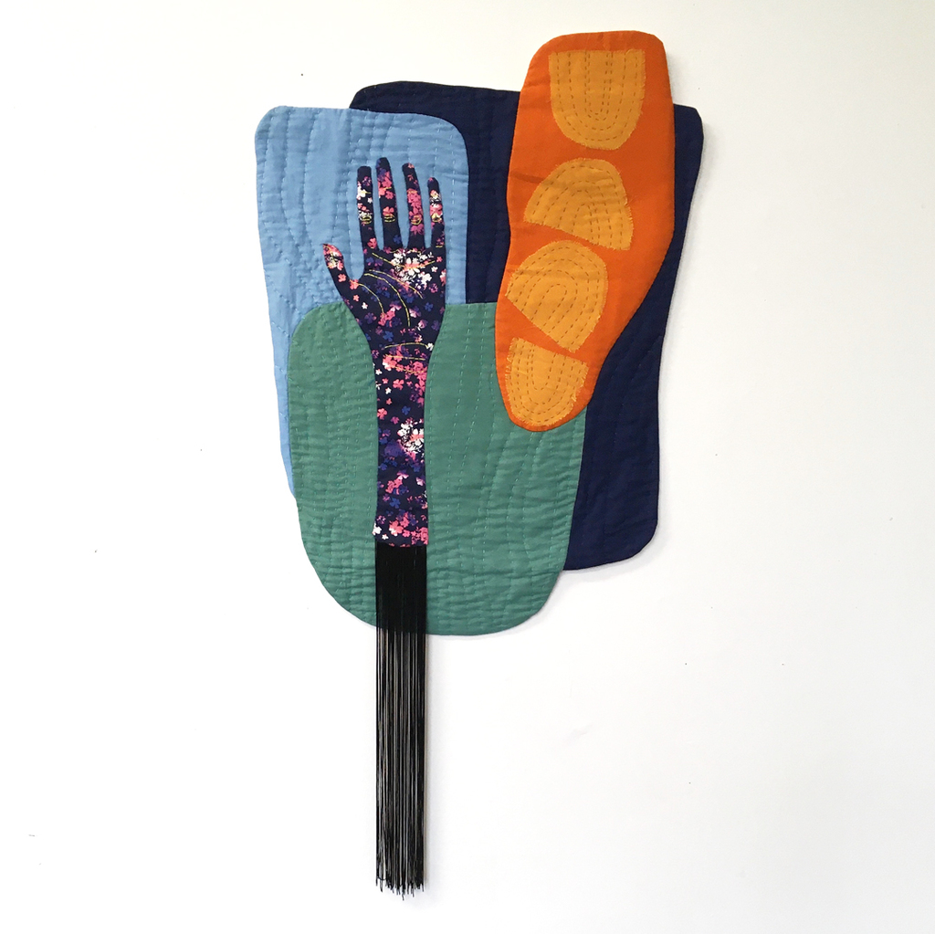 Quilted fabric image of abstract shapes and a hand