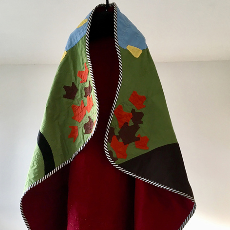 Quilted fabric image of dog and forest scene hanging on a hook